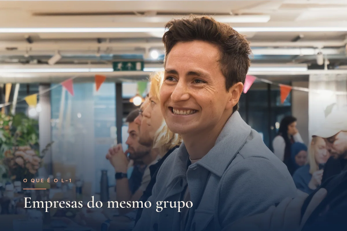 Homem sorrindo em ambiente de escritório aberto, conversando com colegas